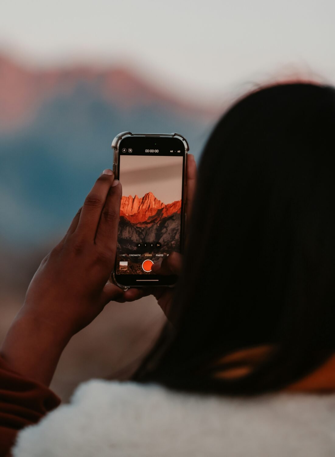 Woman photographing mountain panorama with smartphone for custom acrylic snowboard print