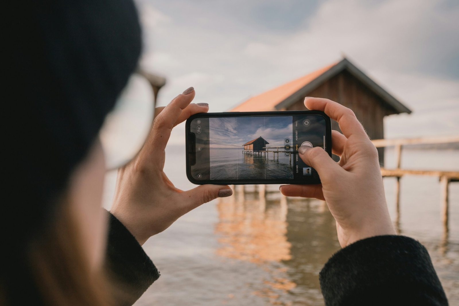 woman taking a photo of a house on the beach with a smartphone - printmyjourney Montreal
